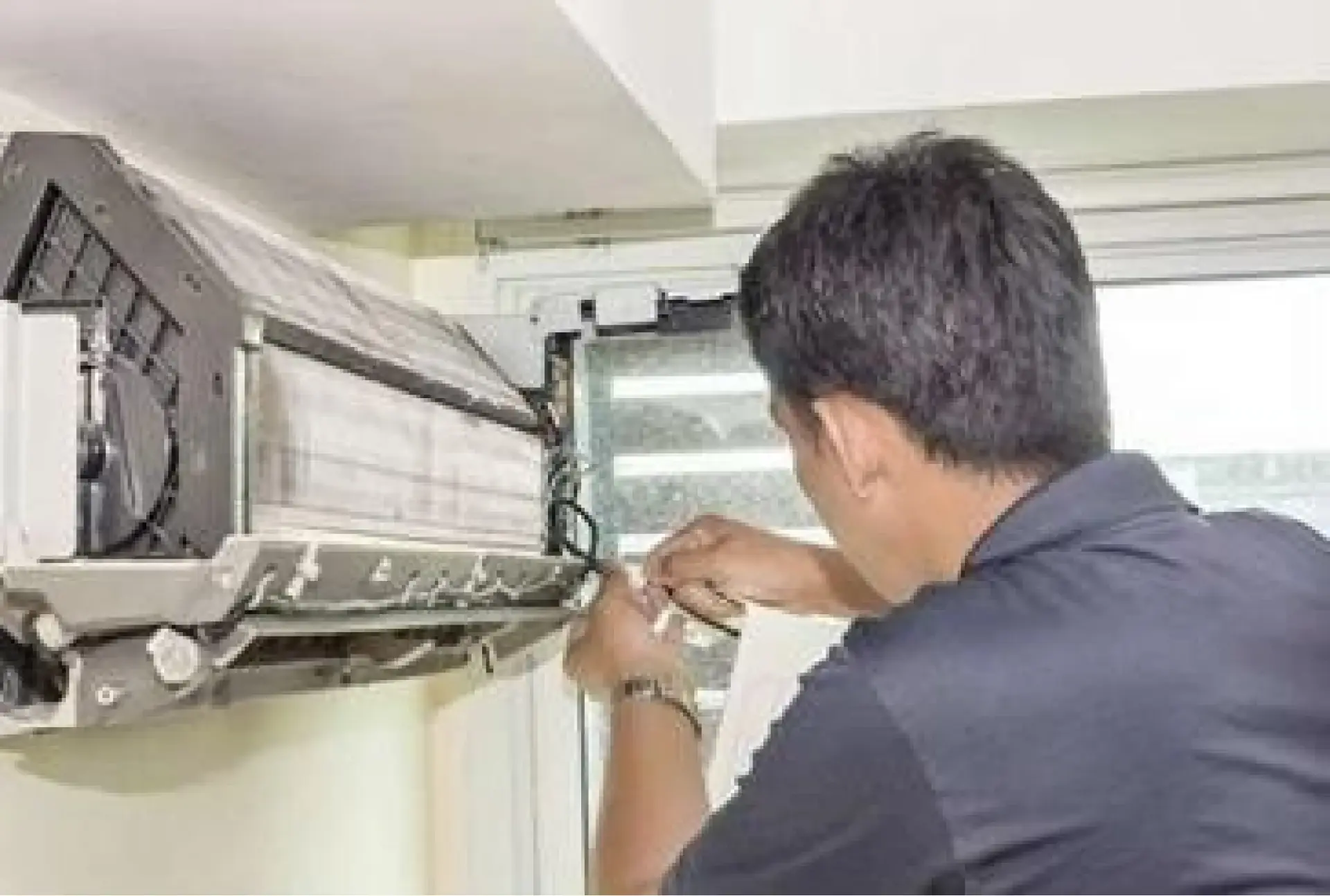 Technician maintaining a wall-mounted air-conditioning unit